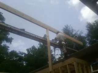 Carpenter setting a ridge beam over a new addition frame — Ice Dam Removal by Roofing Brothers in Oglesby