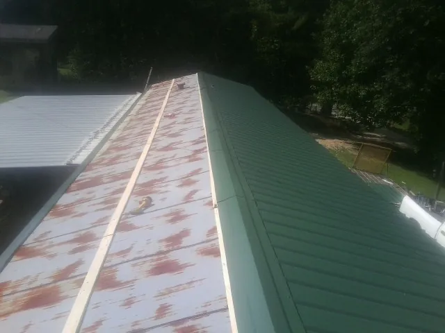 Old rusted panels beside newly installed green metal roofing — Wind Damage Roof Repair by Roofing Brothers in Oglesby