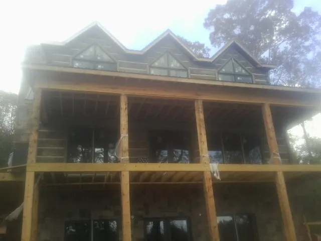 Dormers and porch framing on a large log home under construction — Roof Coating work by our crew in Oglesby