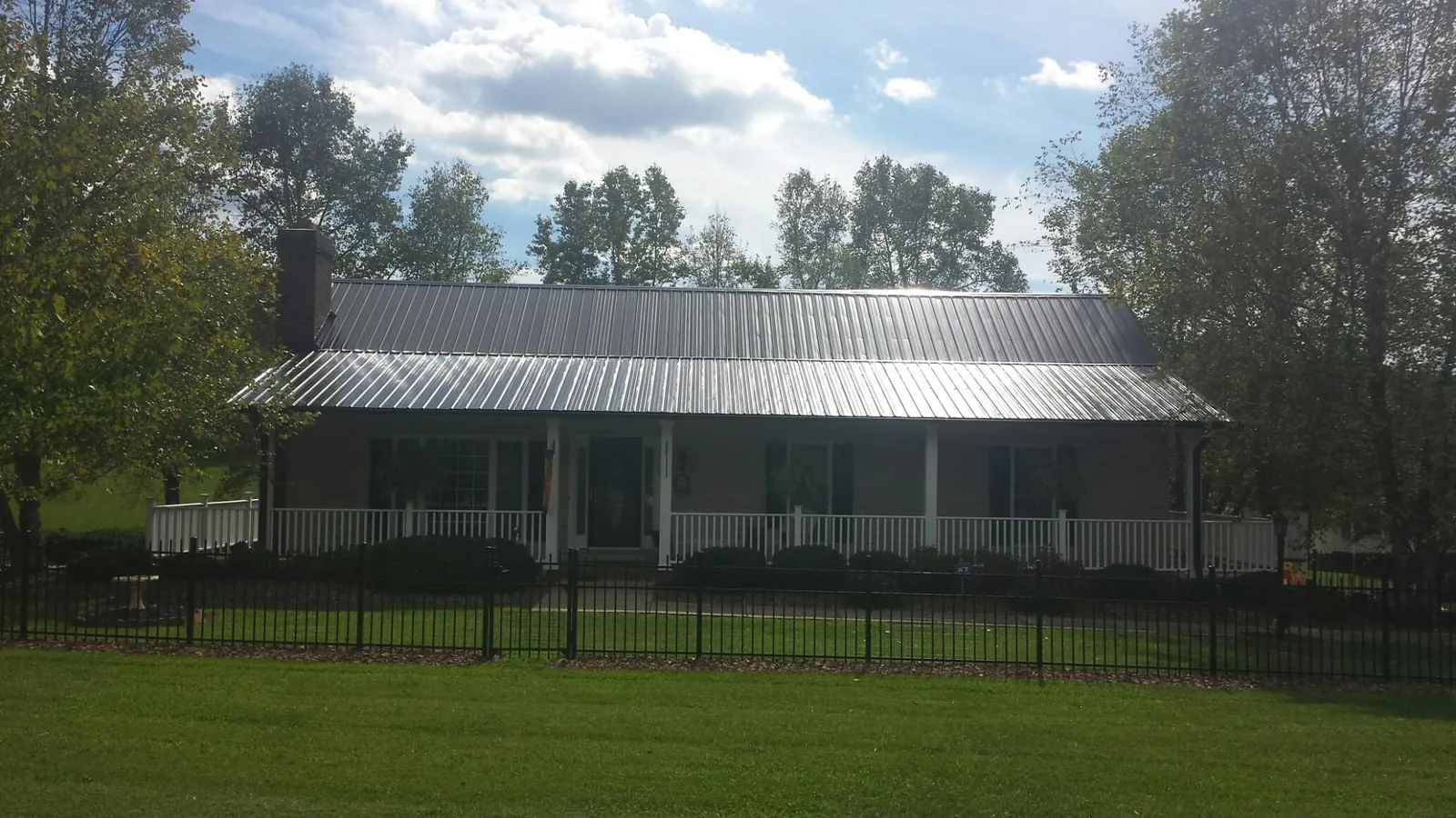 Gray metal roof on a brick ranch with a full width front porch — Gutter Guard Installation work by our crew in Oglesby
