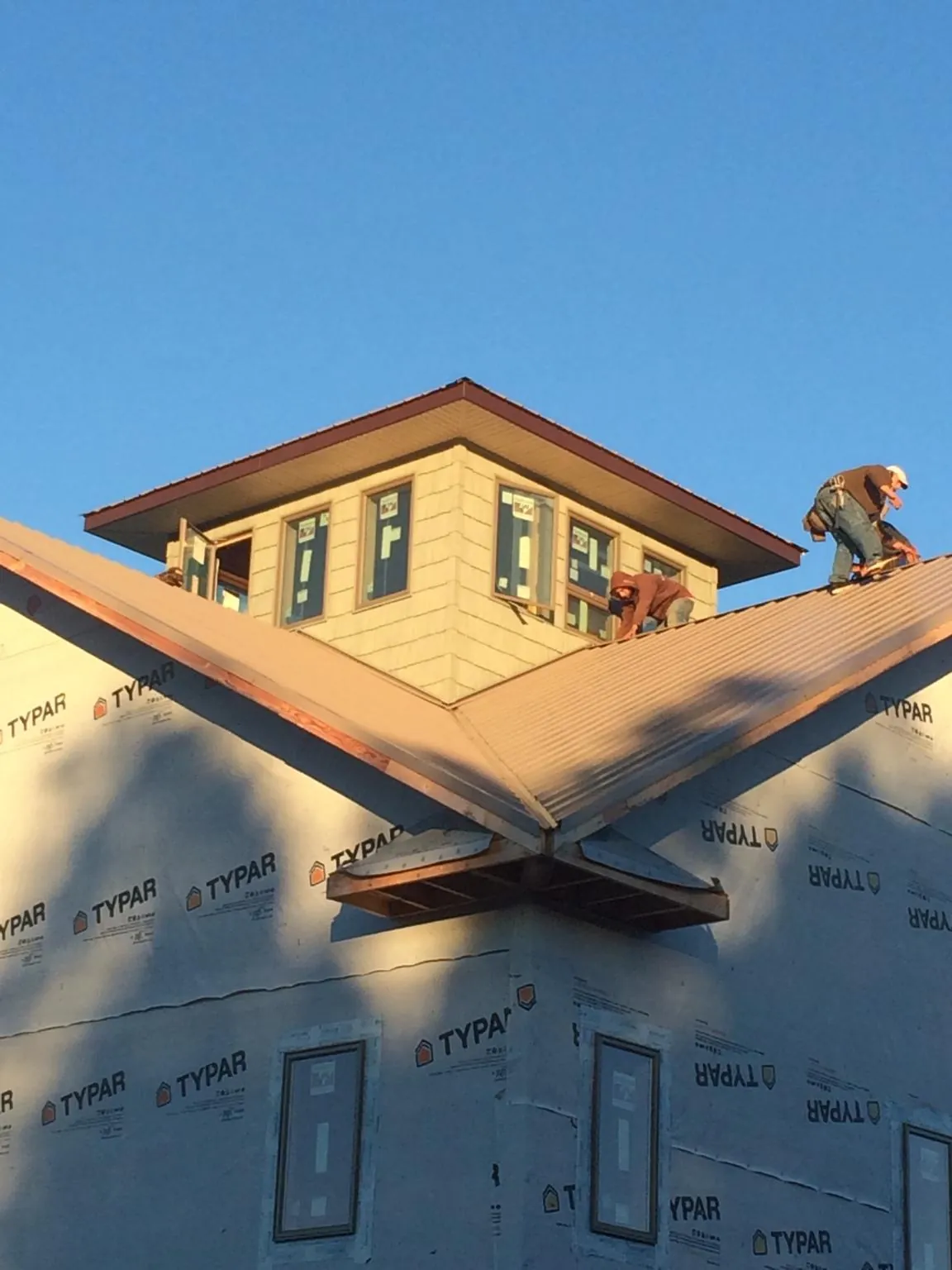Roofers working around a rooftop cupola on a new metal roof at sunset — Roof Waterproofing in Oglesby by Roofing Brothers